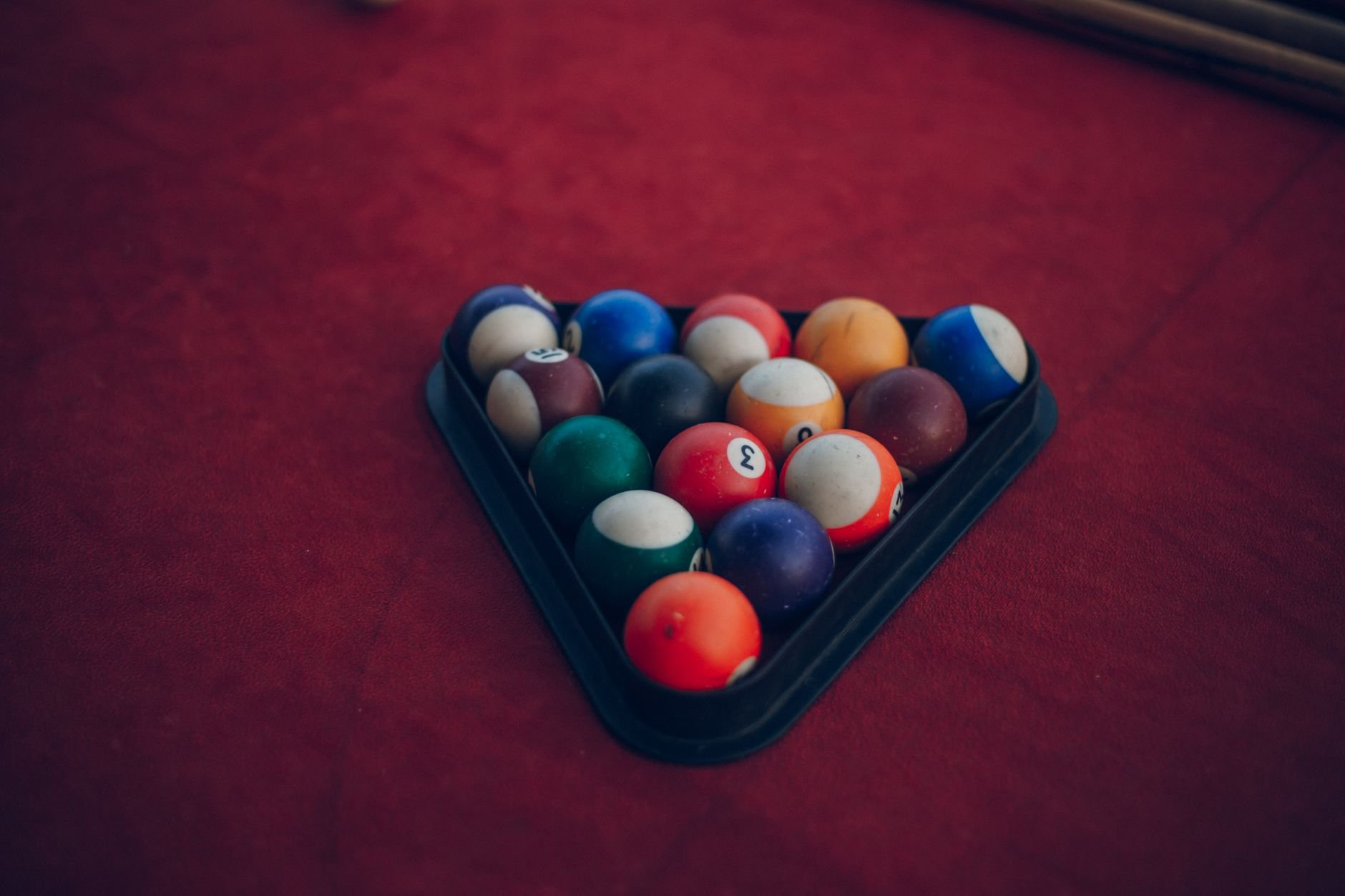 Colorful billiard balls arranged in a triangle rack on a pool table.