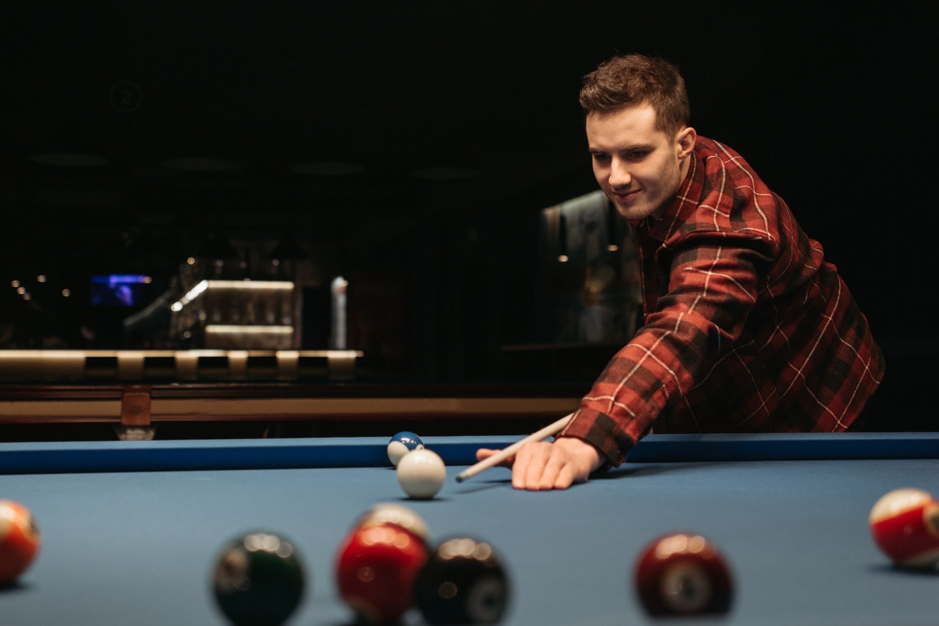 A man playing billiards on a pool table indoors.